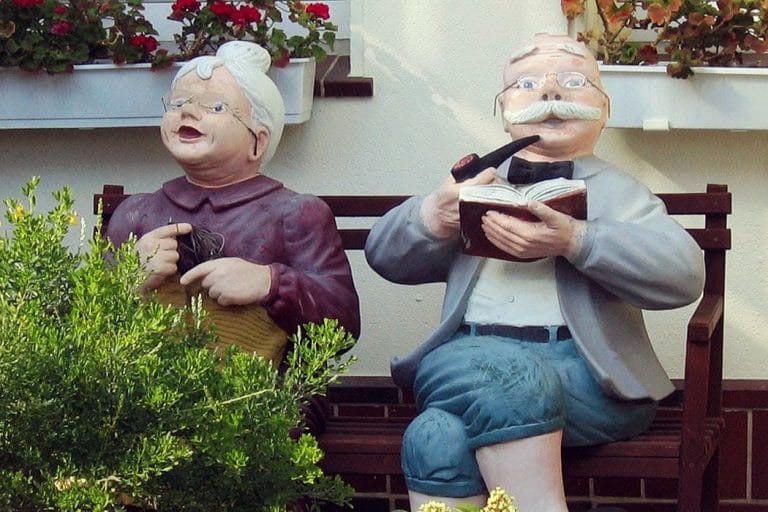 Älteres Ehepaar als Puppen auf einer Bank
